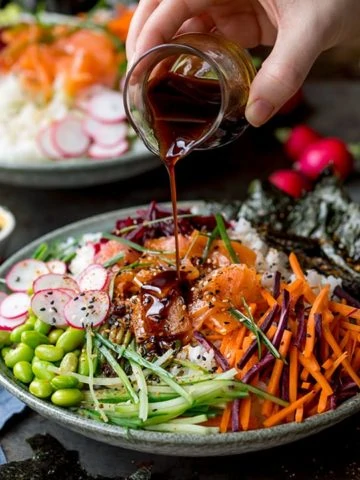 Pouring soy dressing on a sushi salmon bowl