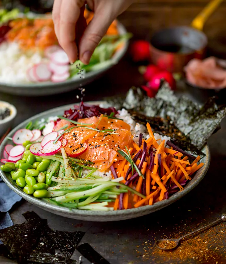 Sprinkling sesame seeds on a sushi salad bowl