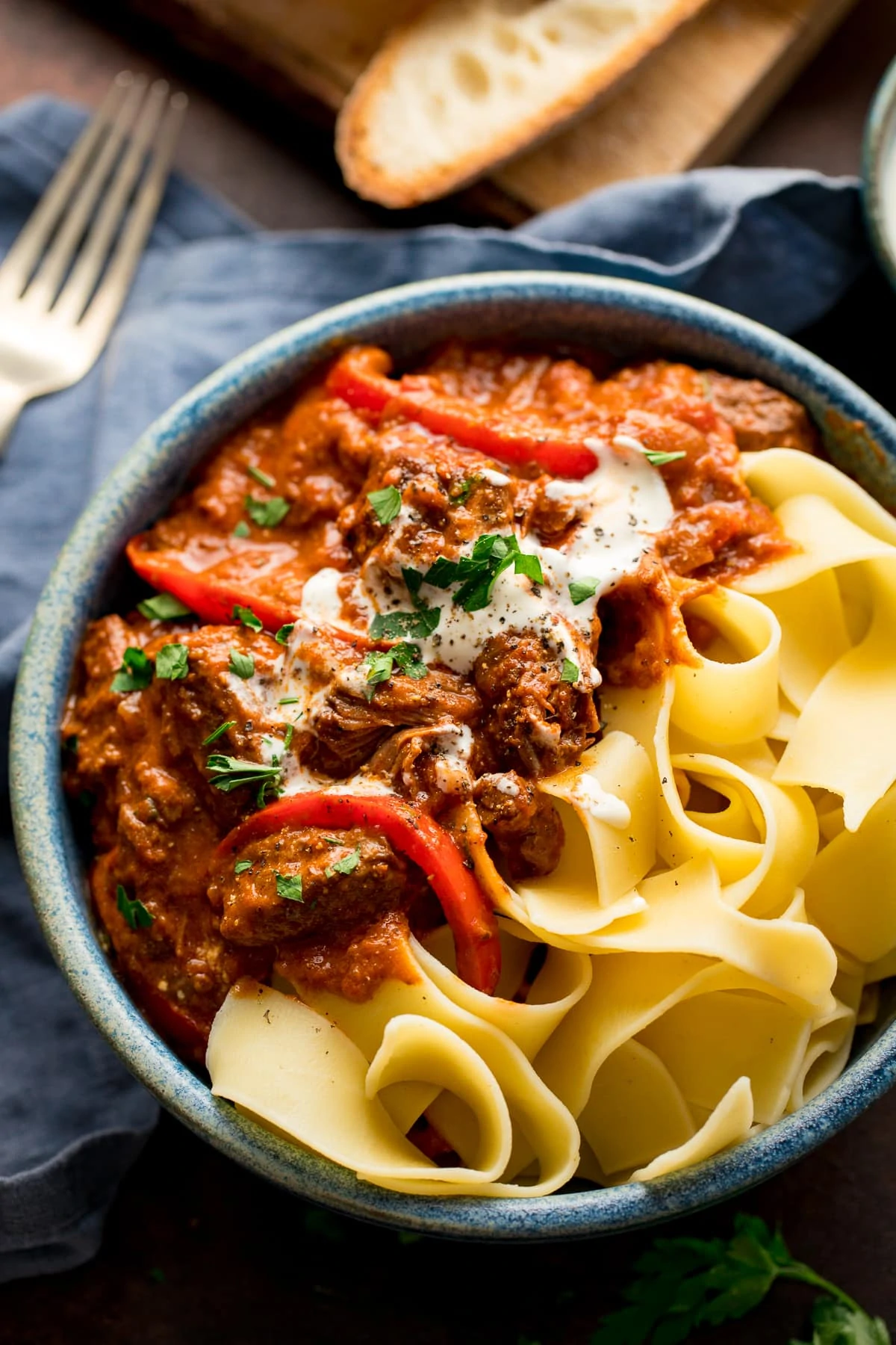 Beef Goulash in a blue bowl with pappadelle pasta