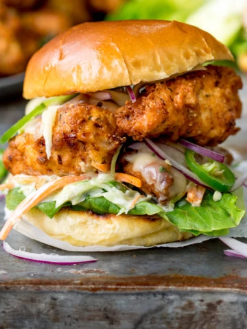 Square image of Crispy chicken burger on a brioche bun with lettuce.