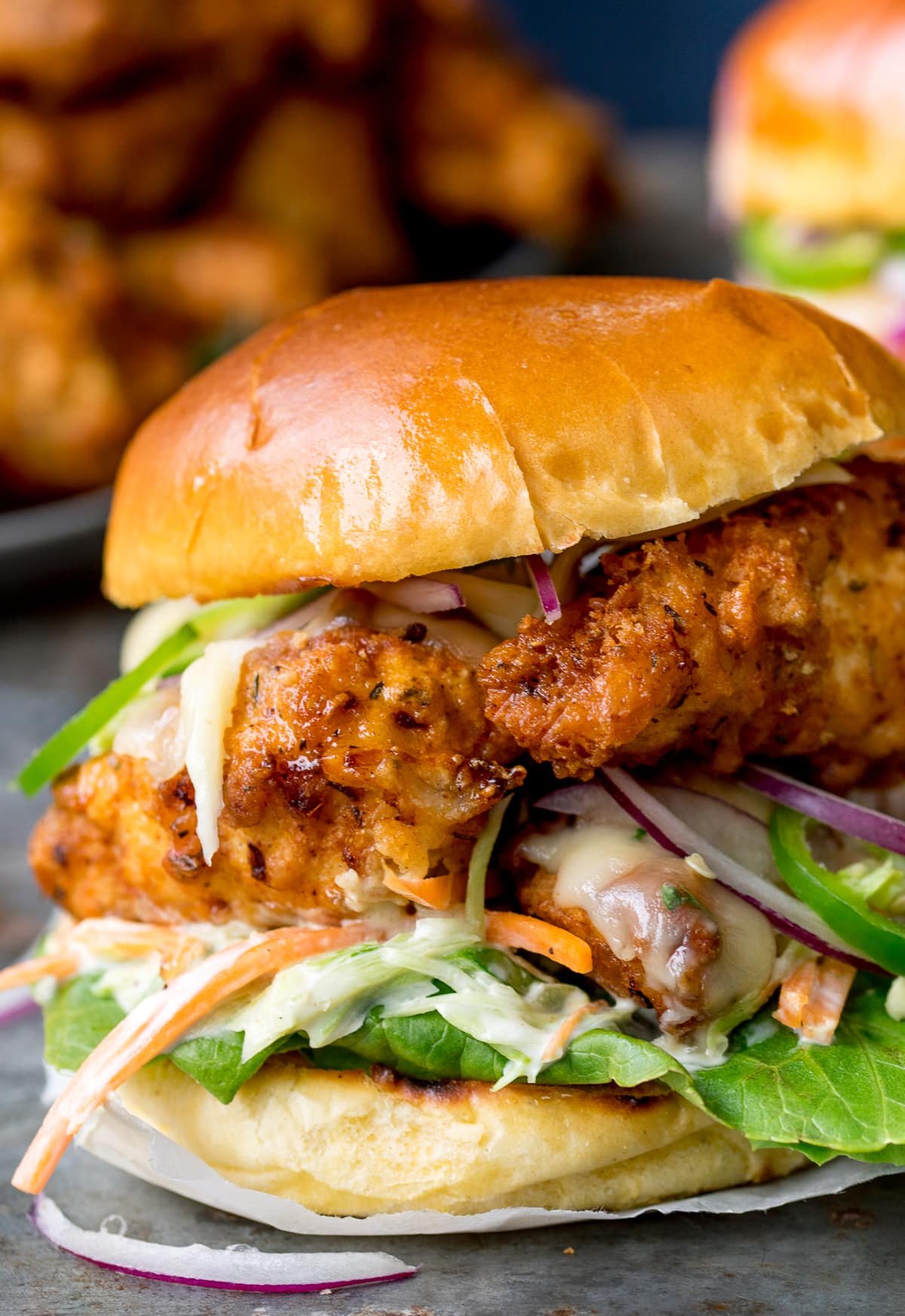 Nahaufnahme eines Crispy Chicken Burgers auf einem Brioche-Brötchen mit Salat.