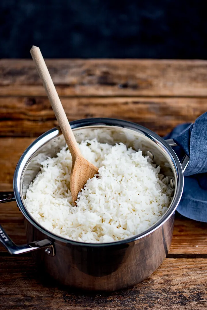Boiled rice in a pan with a wooden spoon in pan