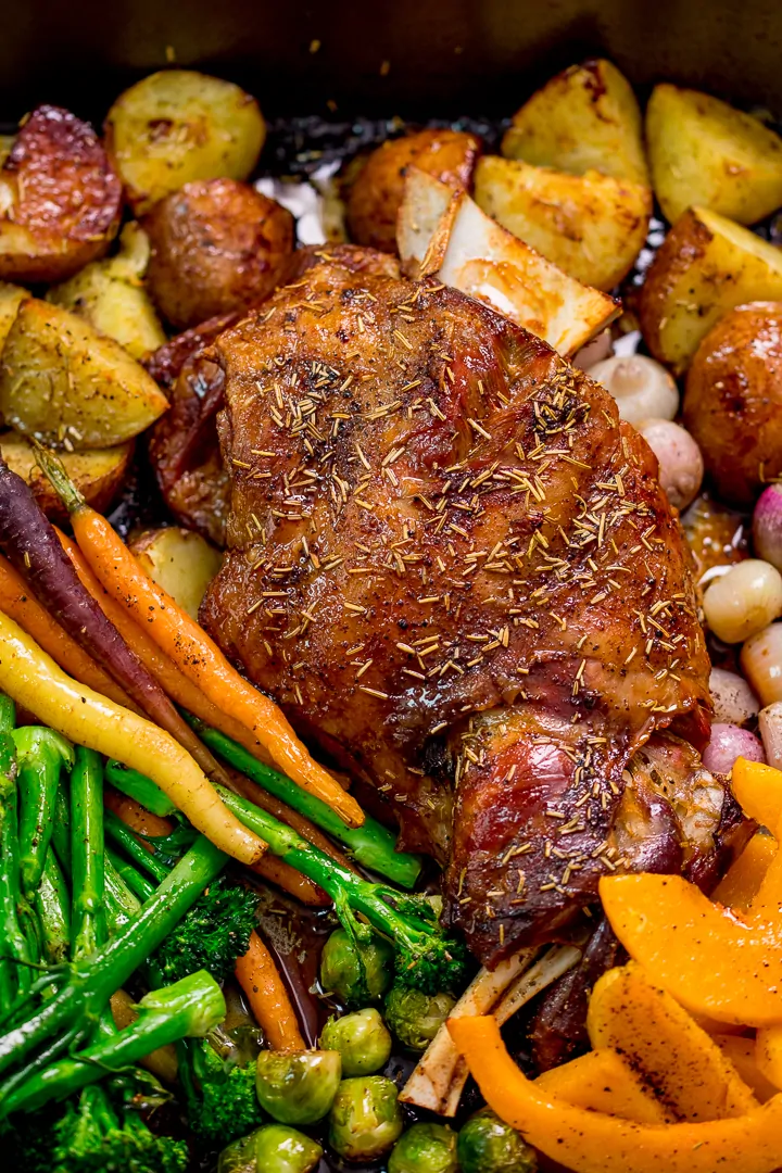 Close up of roast lamb shoulder and vegetables in a roasting tin