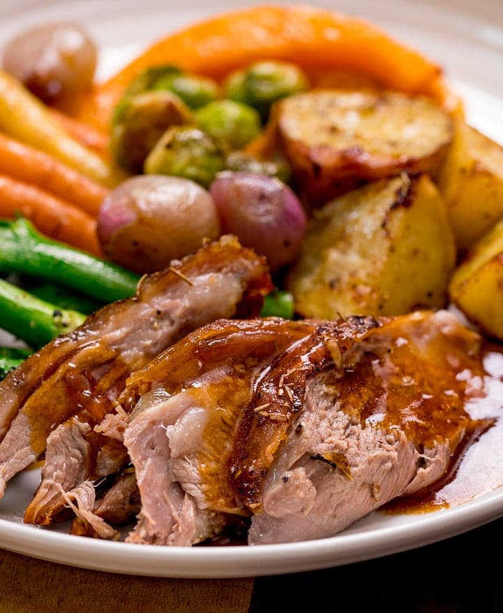 Close up image of lamb, vegetables and gravy on a white plate
