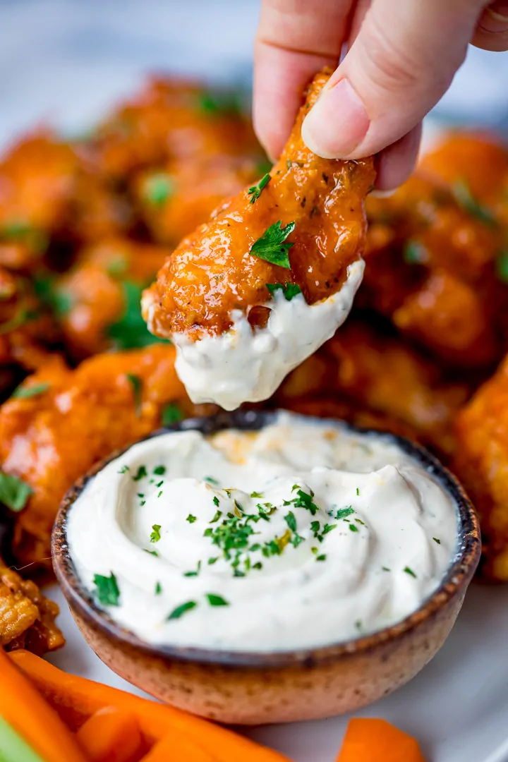 Buffalo chicken wing being dipped in blue cheese sauce
