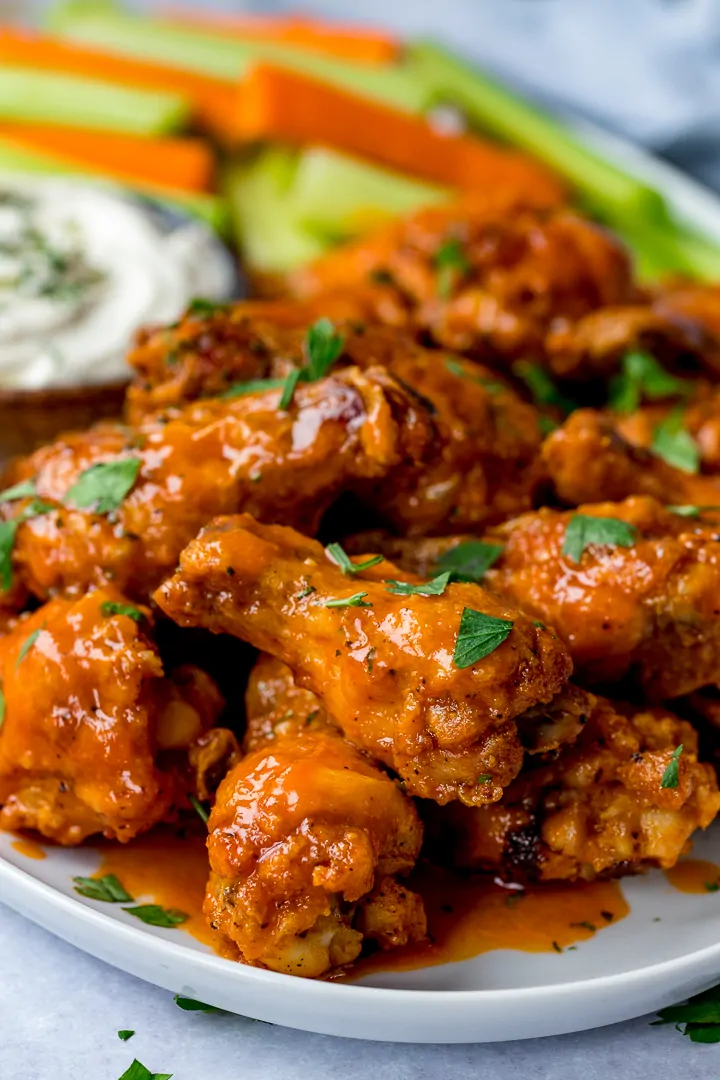 Buffalo chicken wings in a white plate with carrot and celery