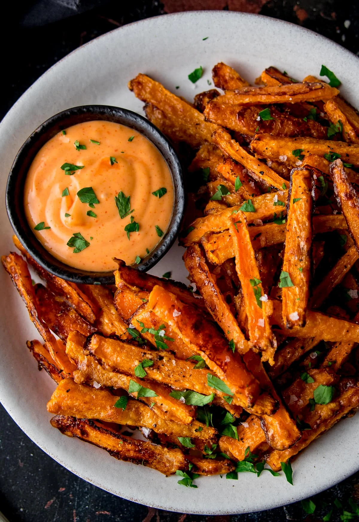 Close up overhead shot of carrot fries on a white plate with dipping sauce