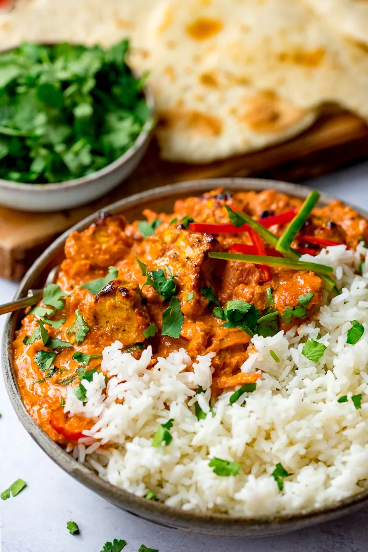 Bowl of chicken tikka masala with rice and flatbreads