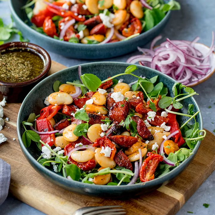 Chorizo and Lima Bean Salad in a bowl on a wooden board