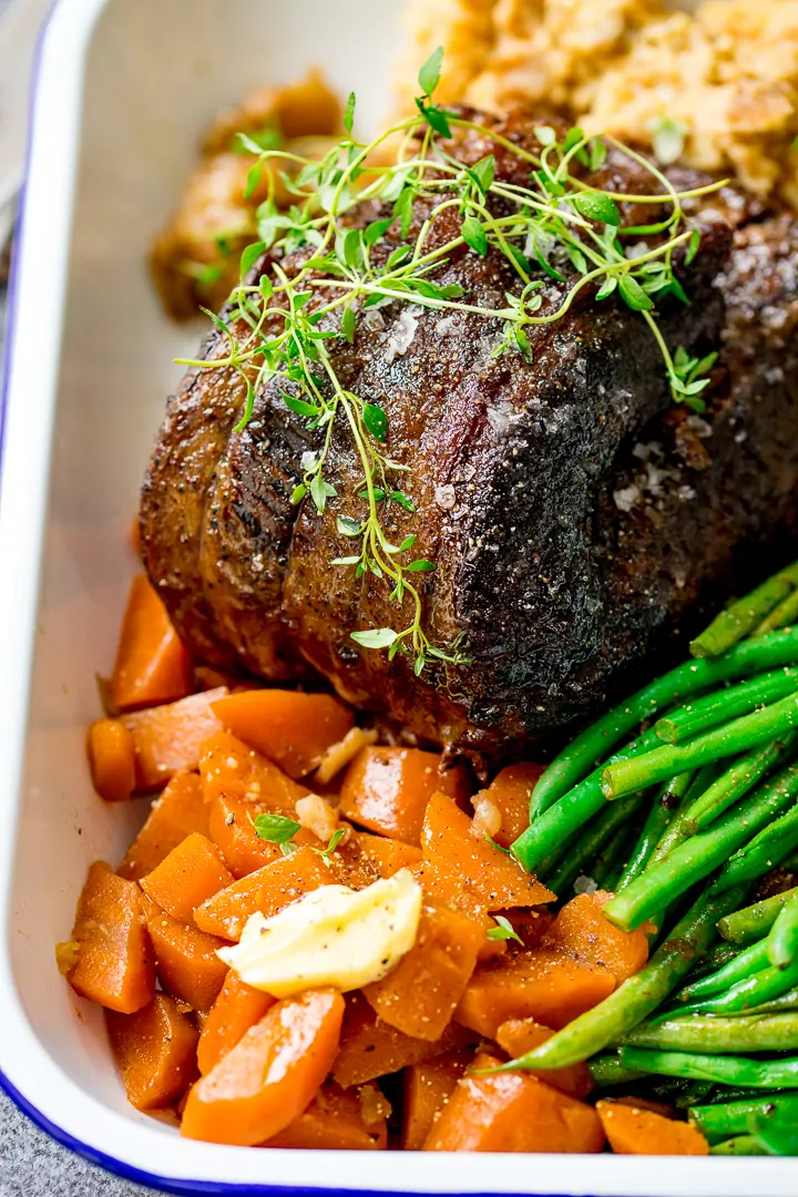 Pot roast beef and vegetables in a white serving dish