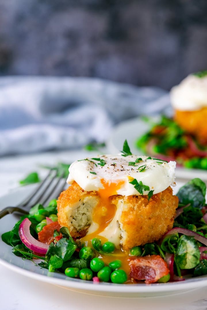 pea and bacon salad topped with a fish cake and poached egg on a light background