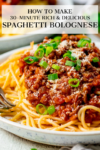 spaghetti bolognese on a white plate with spring onions sprinkled on top. Text overlay on image.