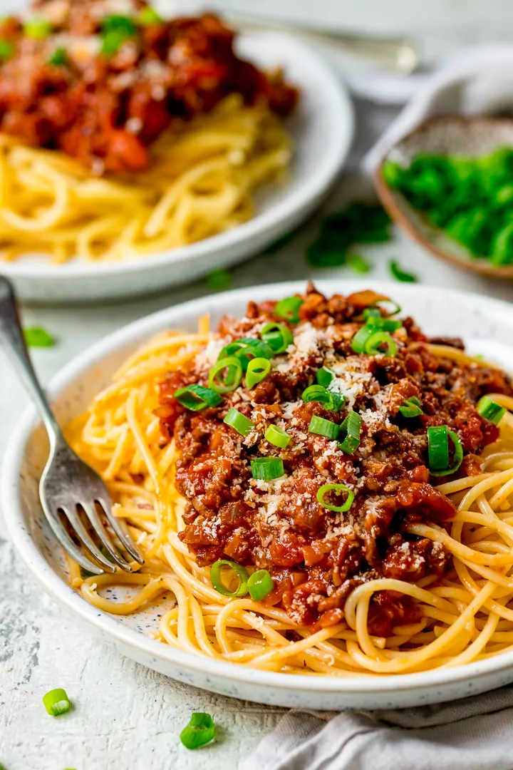 Spaghetti bolognese on a white plate - further plate in the background