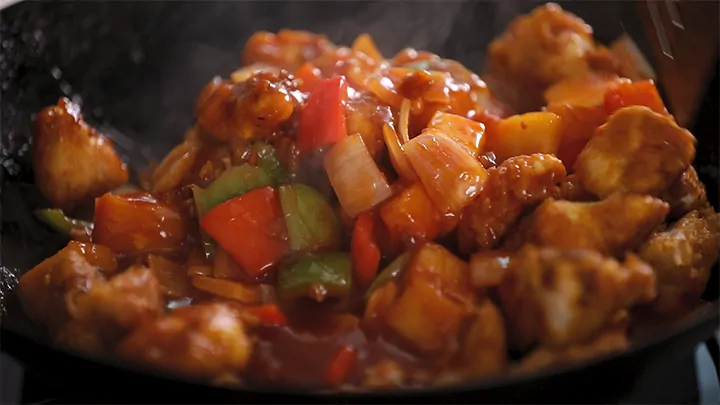 Close up image of sweet and sour chicken in a wok