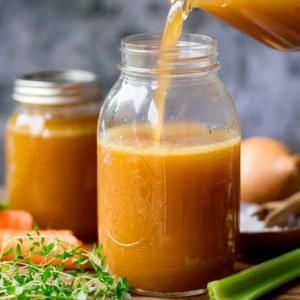 Chicken stock being poured into a glass jar