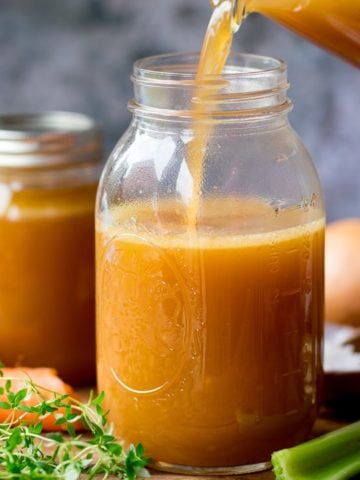Chicken stock being poured into a glass jar