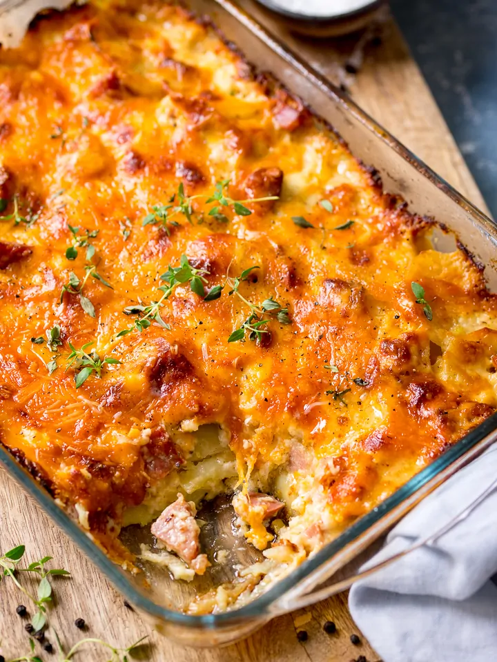 Scalloped potatoes with ham in a baking dish, scoop removed