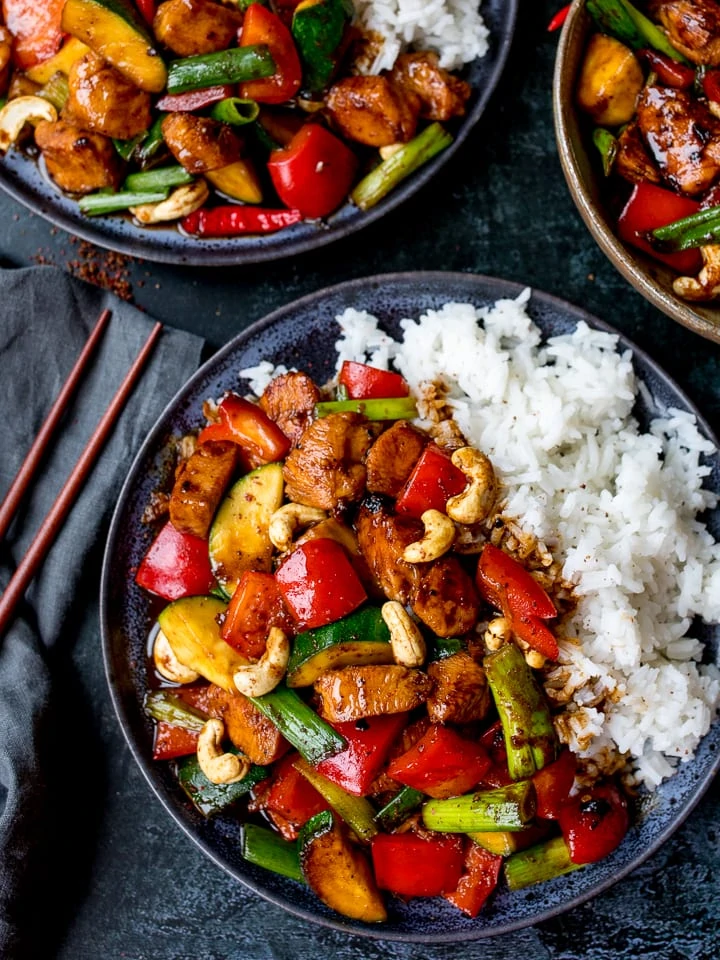 Kung pao chicken on a dark plate with rice