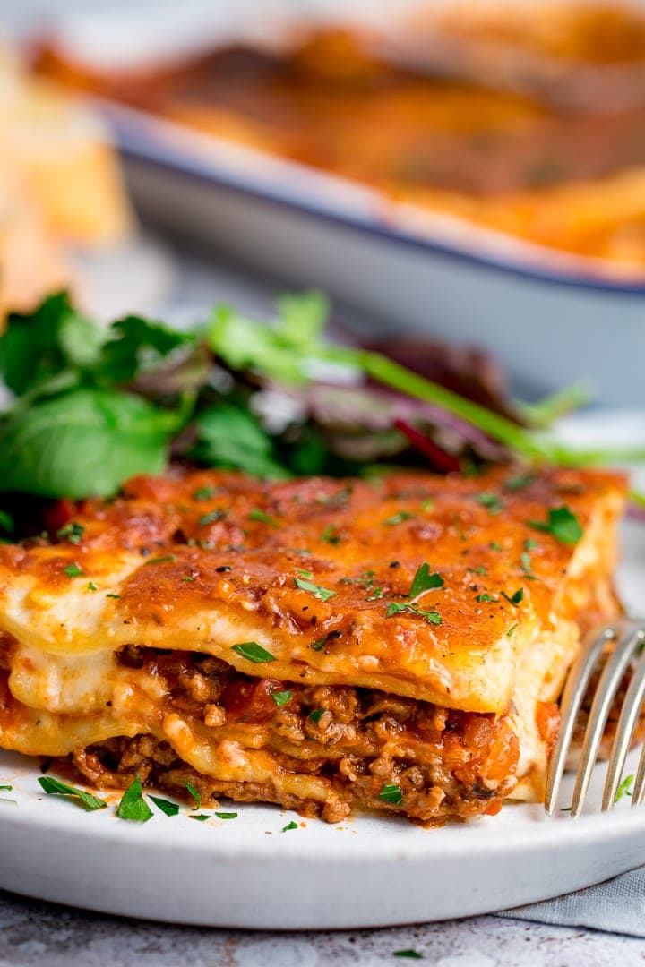 Portion of lasagne on a light plate with salad