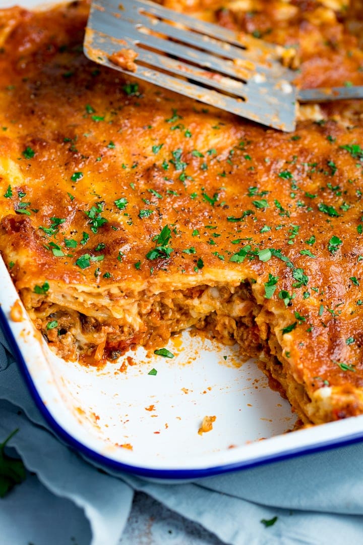 Close up image of a dish of lasagne with a portion taken out