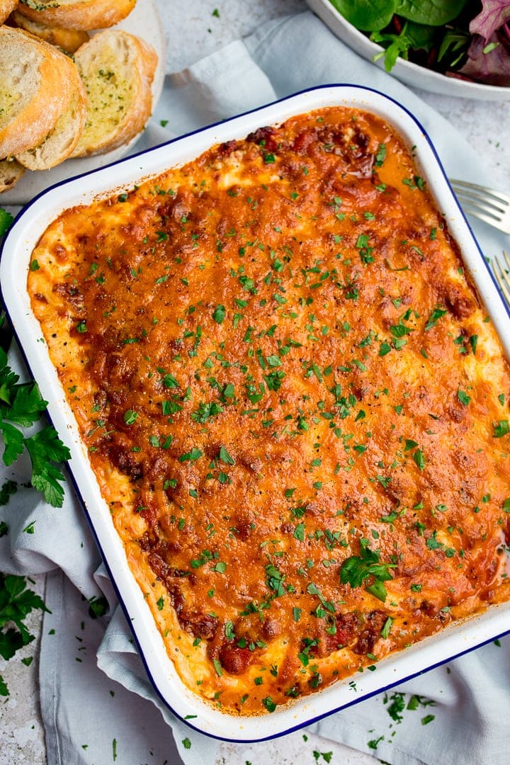 Overhead image of a dish of lasagne on a light background