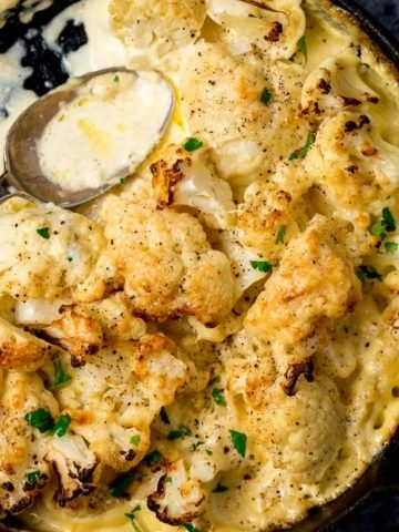 Cauliflower cheese in a pan with a spoon in pan