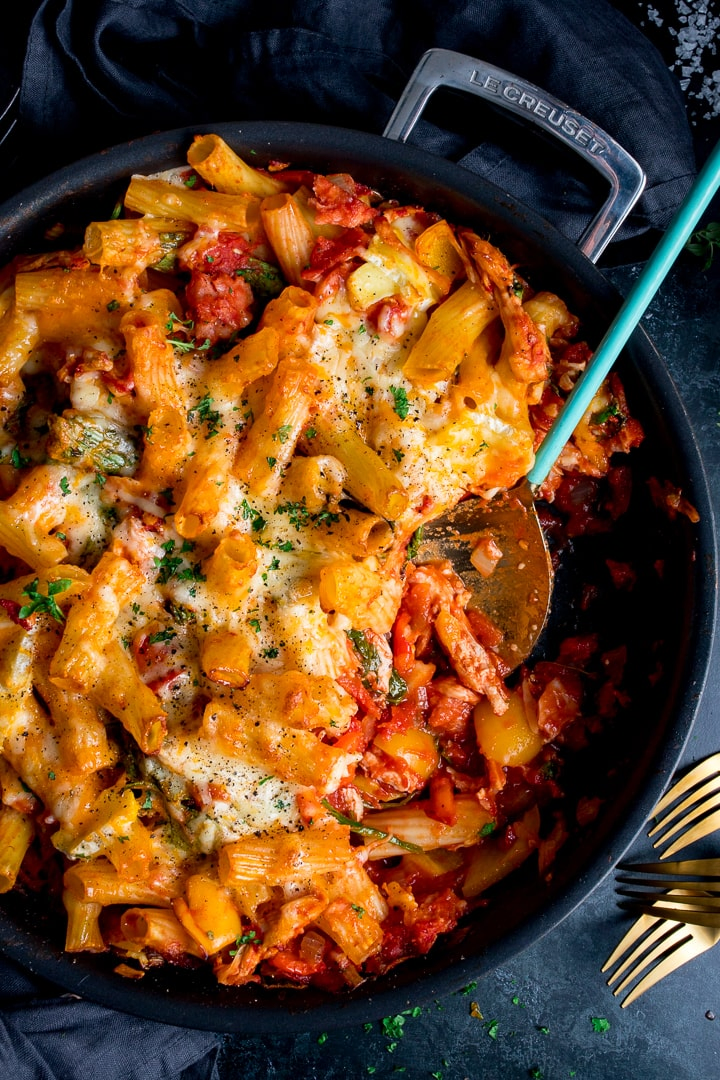 Leftover turkey, ham and cheese pasta bake in a black pan with a scoopful being taken