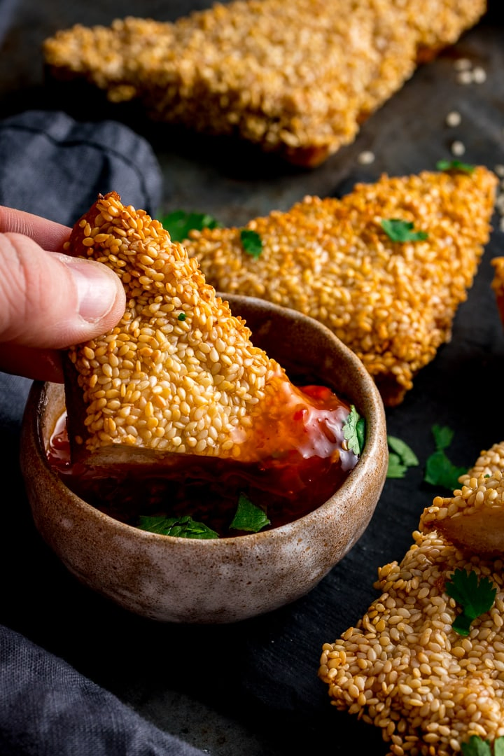 Prawn toast being dipped into sweet chilli sauce