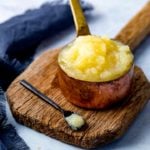 Apple sauce in a copper pan on a wooden board against a light background