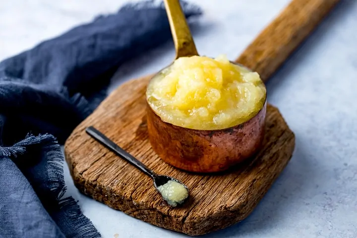 Apple sauce in a copper pan on a wooden board