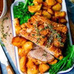 Overhead of roast pork with crackling on a tray with roast potatoes and broccoli