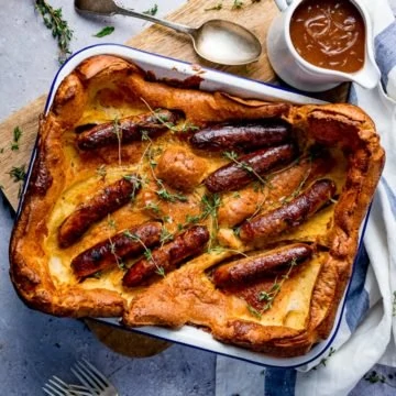 Overhead of toad in the hole on light background with jug of gravy