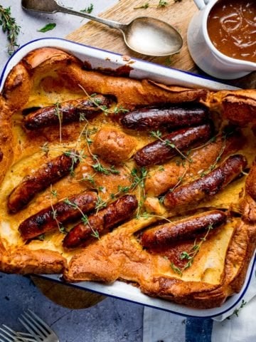 Overhead of toad in the hole on light background with jug of gravy
