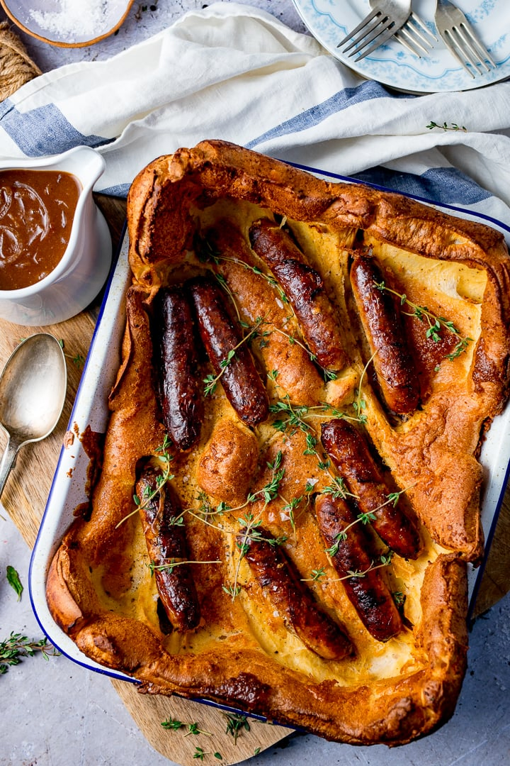 toad in the hole on light background with jug of gravy