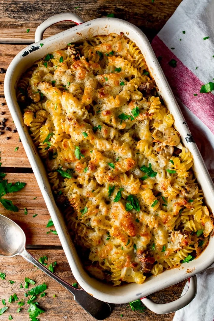 chicken alfredo pasta bake in a white tin on a wooden background