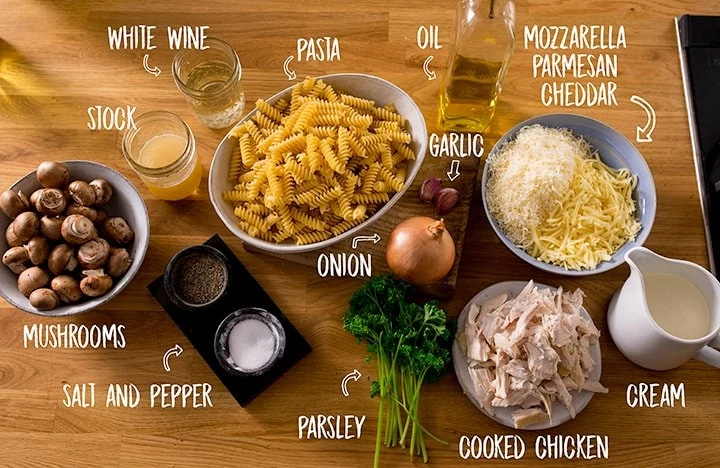 Ingredients for chicken alfredo pasta bake on a wooden table
