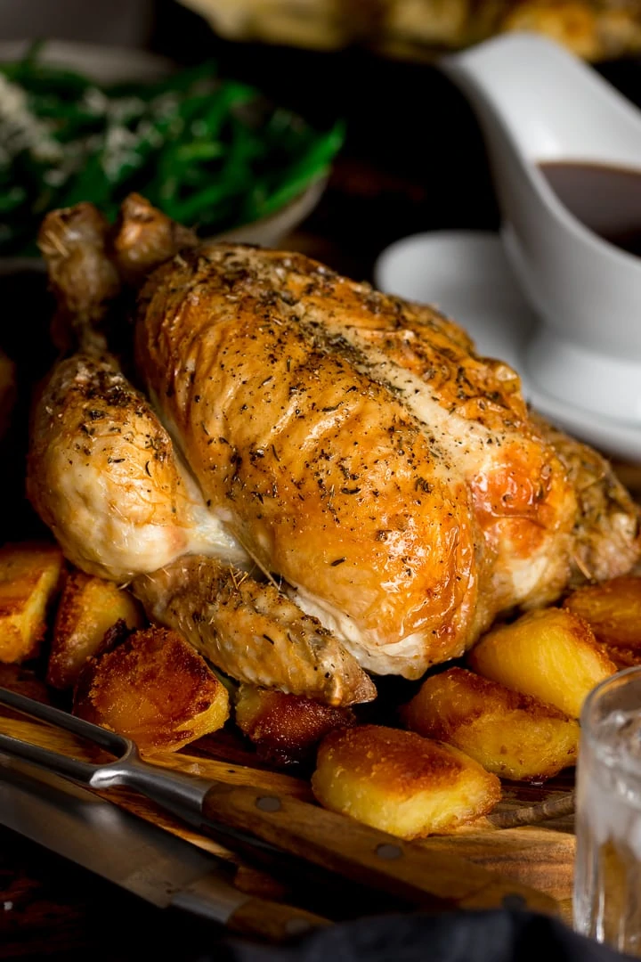 roast chicken on a board with roast potatoes