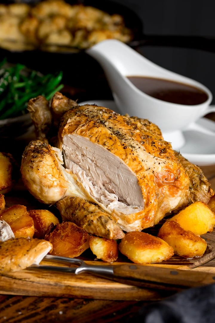 roast chicken with a slice taken out on a board with potatoes