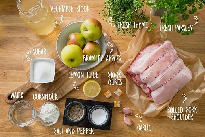 Ingredients for roast pork with apple sauce and gravy on a wooden table