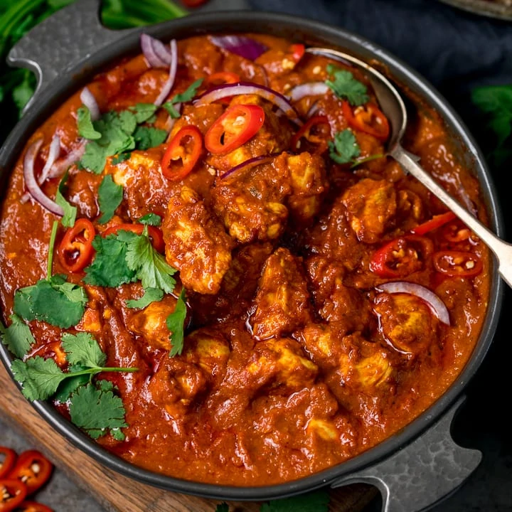 chicken madras in a serving bowl topped with chilles and coriander