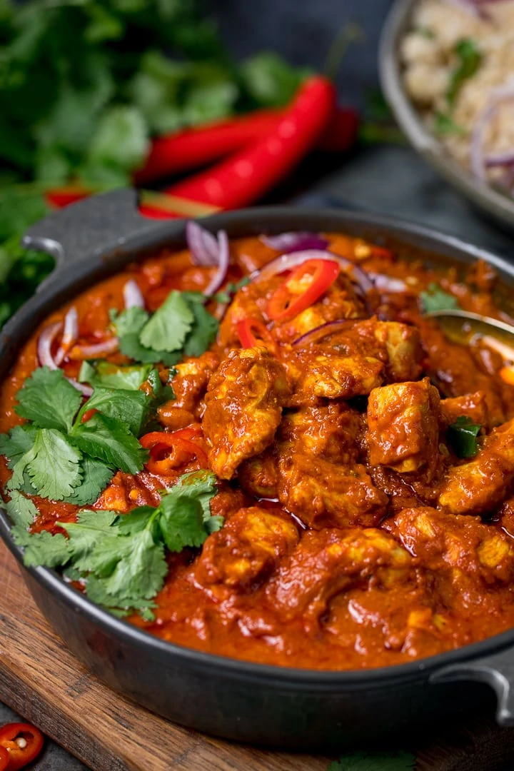 chicken madras in a dark serving bowl on a wooden board