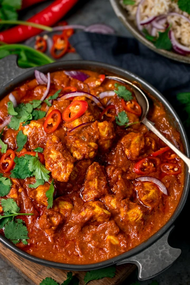 chicken madras in a dark serving bowl with a spoon in the bowl