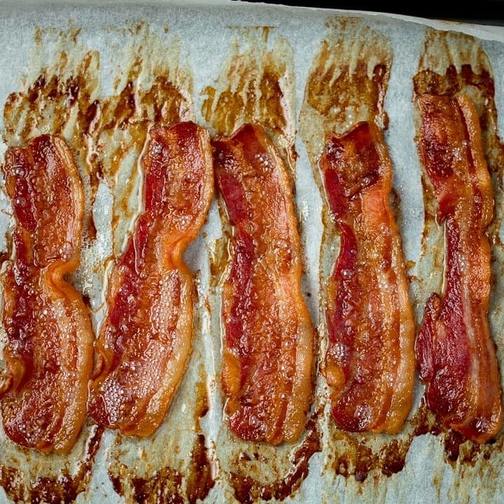 Square image of strips of cooked bacon on a tray