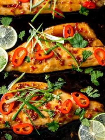 Asian-style sea bass fillets on a baking tray with spring onions and chillies