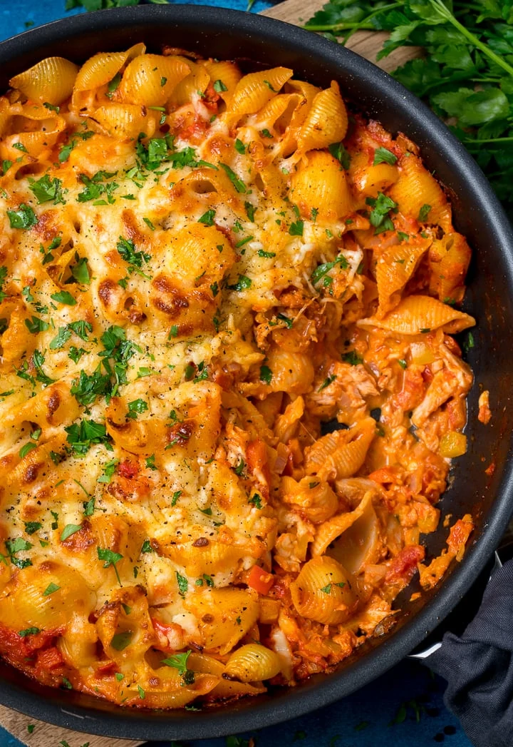 tuna tomato pasta bake in a dark pan topped with parsley