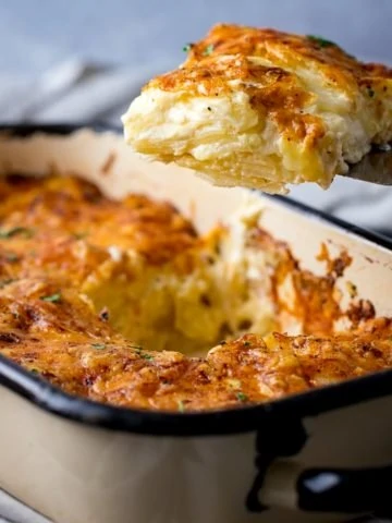 A scoop of Dauphinoise Potatoes being taken out of the dish