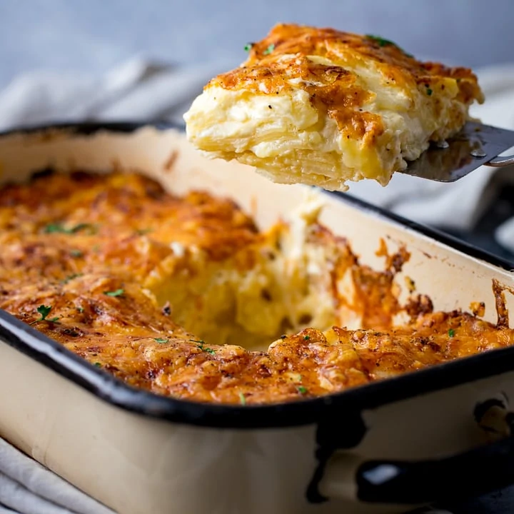 A scoop of Dauphinoise Potatoes being taken out of the dish