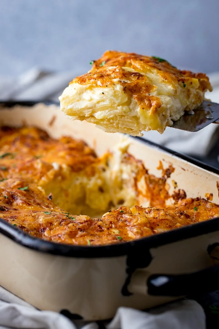 Dauphinoise Potatoes being scooped out of a baking dish