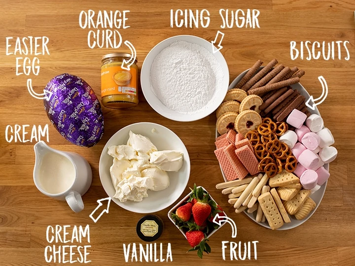 Ingredients for making Creme Egg Cheesecake Dip on a wooden table