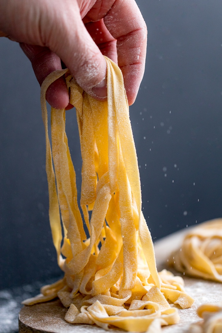 homemade tagliatelle being lifted off a board